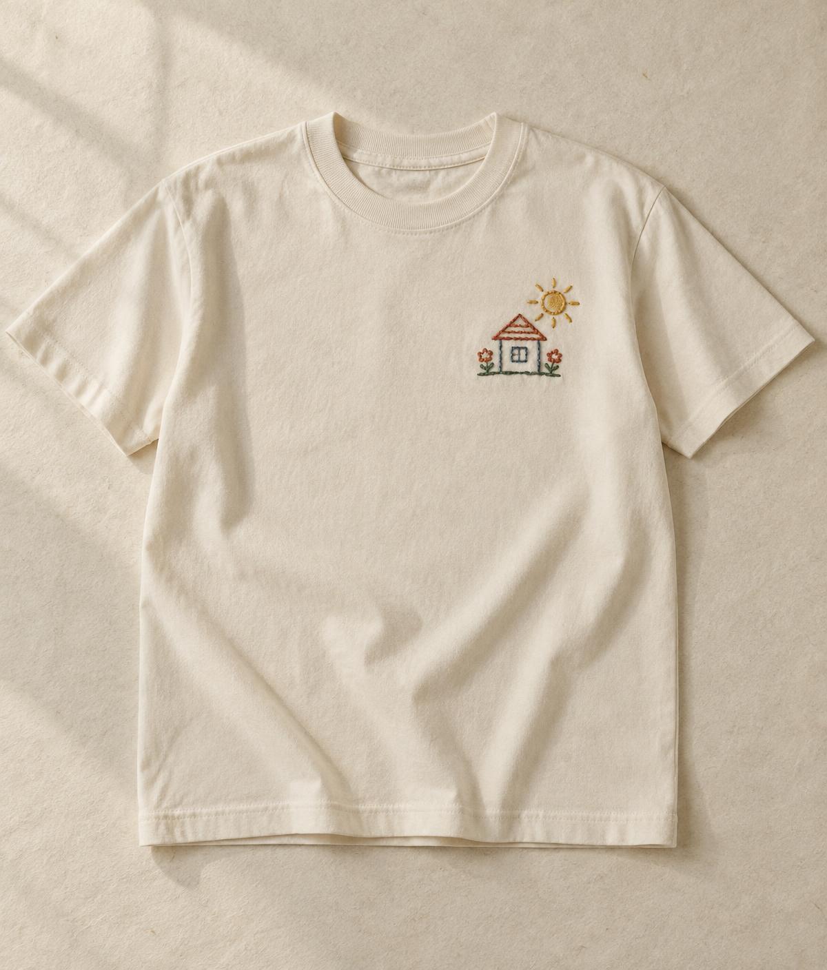Ivory T-shirt with a small embroidered child's drawing of a house, sun and flowers
